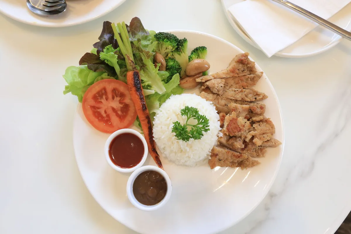 Plato de almuerzo con arroz, pollo y ensalada