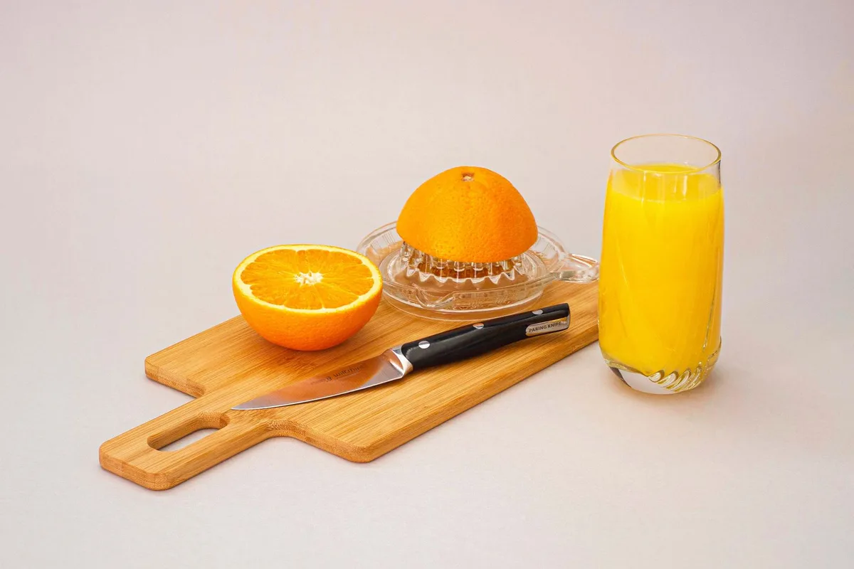 Cítrico partido junto a un vaso de jugo recién exprimido