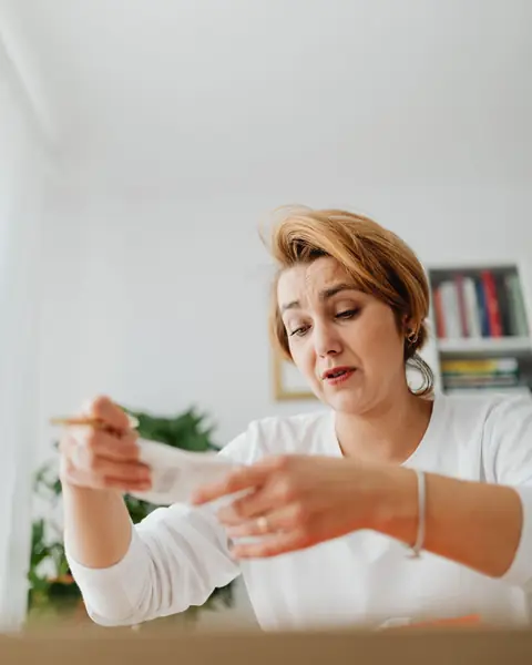 Mujer preocupada leyendo un papel en su casa